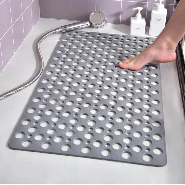 Graue Duschmatte mit Lochmuster in der Dusche, Fuß auf der Matte