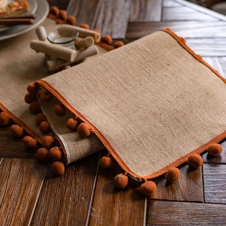 Jute-Tischläufer mit orangefarbenen Pompons