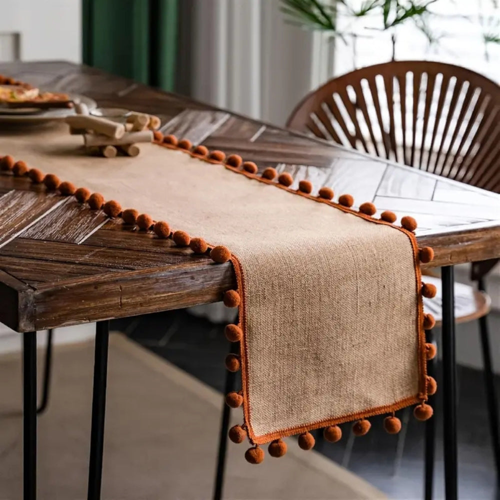 Jute-Tischläufer mit orangefarbenen Pompons